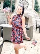 Load image into Gallery viewer, outside patio background with red and blue floral halter mini dress with American flags.
