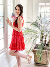 Load image into Gallery viewer, Side view of red floral flows mini dress with tie straps holding American flag
