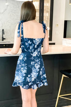 Load image into Gallery viewer, back of navy blue floral dress with tie straps and decorative ruffle
