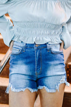 Load image into Gallery viewer, Women&#39;s distressed ripped jean high waisted denim shorts. Paired with a smocked off the shoulder blue women&#39;s blouse. 
