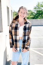 Load image into Gallery viewer, Women&#39;s oversized black, white &amp; brown plaid long sleeve button down shacket. Paired with light denim wash ripped boyfriend jeans. 
