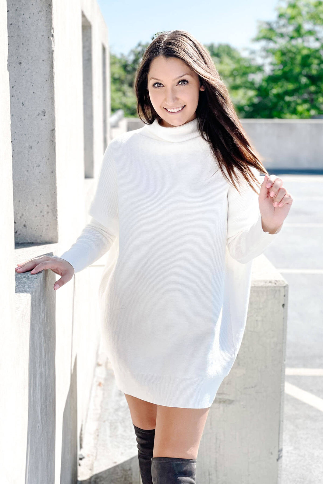 Women's white oversized long sleeve turtleneck sweater dress.  Paired with suede knee high boots. 