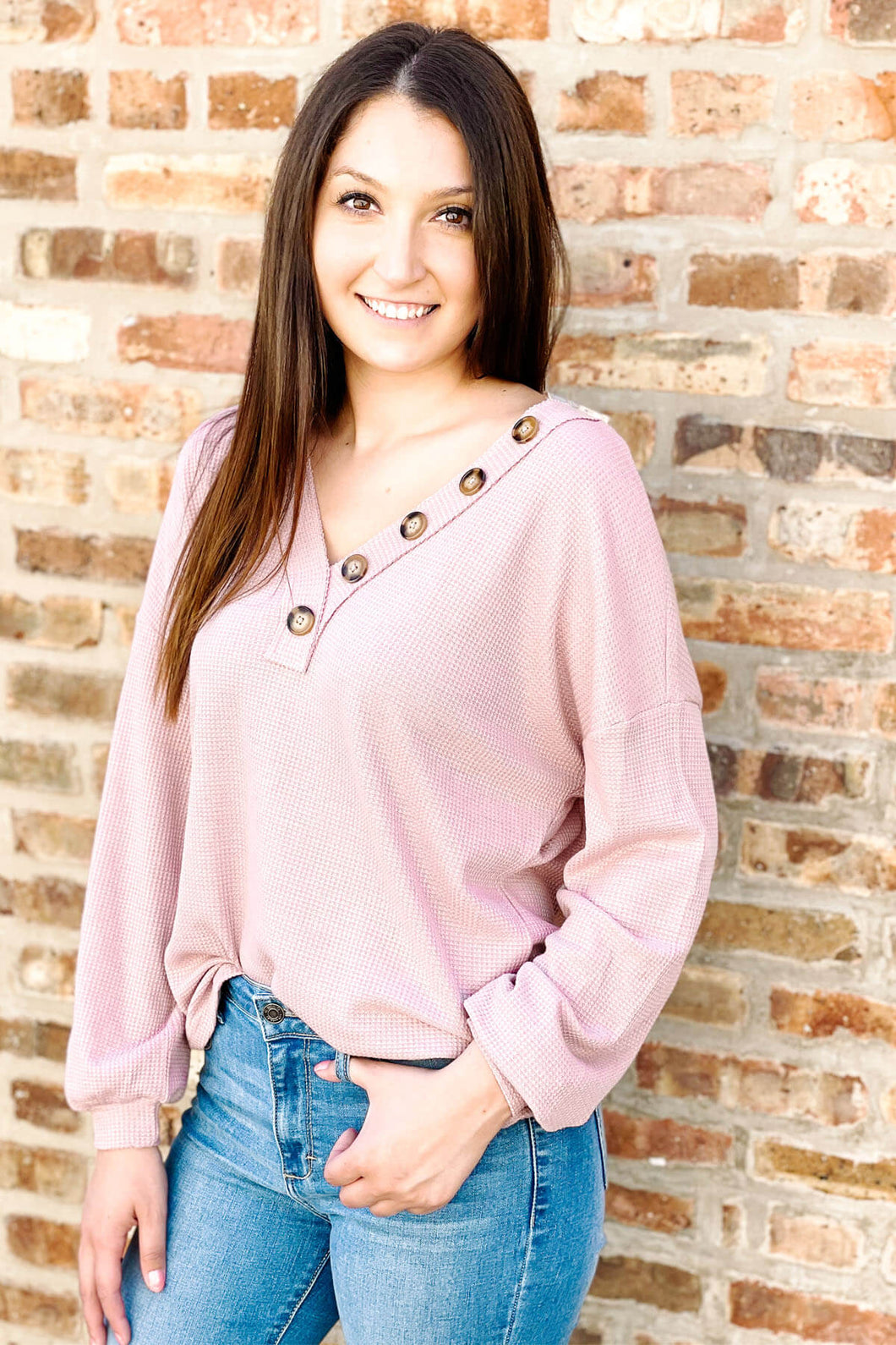 Women's pink waffle knit shirt paired with medium wash distressed skinny jeans