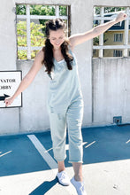 Load image into Gallery viewer, Women&#39;s blue baggy denim relaxed overalls. Paired with a white ripped cropped tank top and white universal threads sneakers
